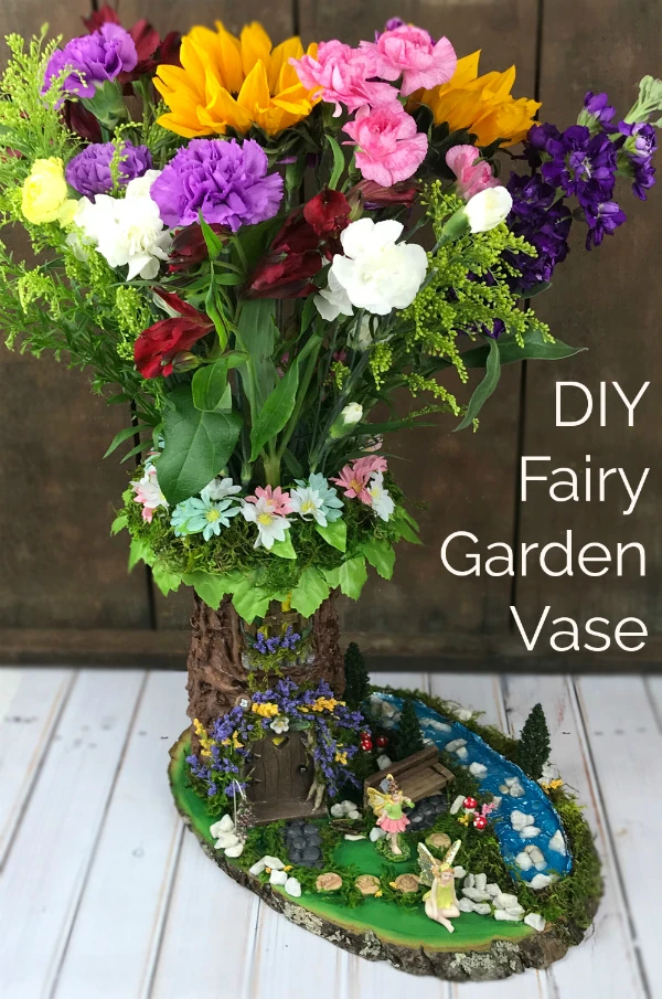 GORGEOUS! Learn how to make a DIY fairy garden vase with a plain florist's vase! This project tutorial shows you how to create this stunning fairy garden scene. It's easier than you might think!